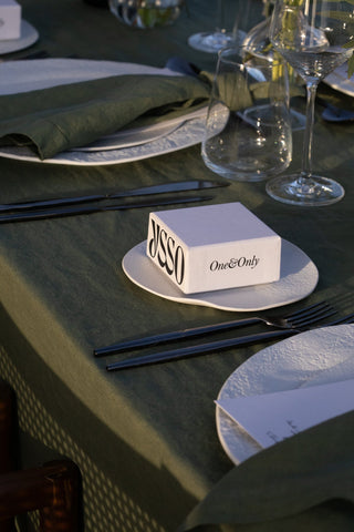 White JOSSO & One&Only branded box on textured white plate at an outdoor table with green napkin and dark fork and chopsticks