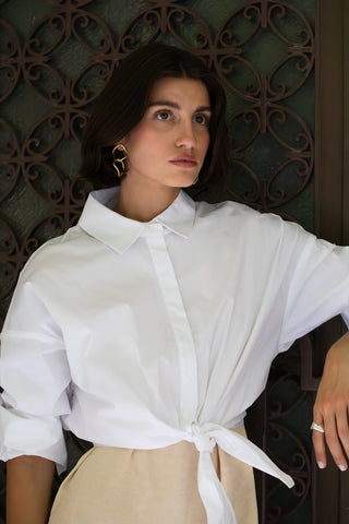 Woman wearing a white blouse with a decorative pattern in the background wearing YSSO chain earrings